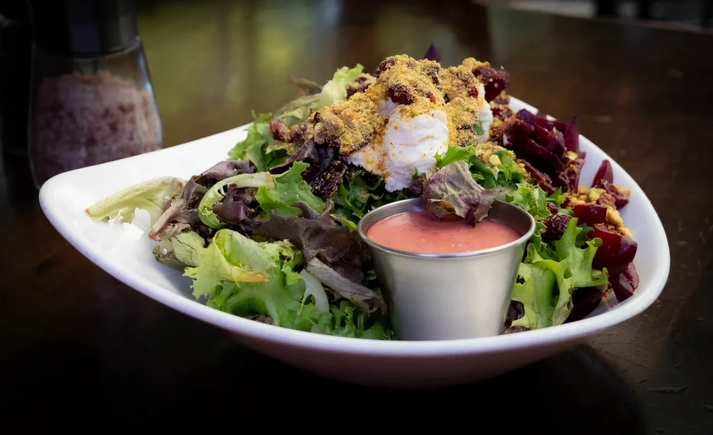 Vibrant salad with mixed greens, beets, cheese, cranberries, and dressing.