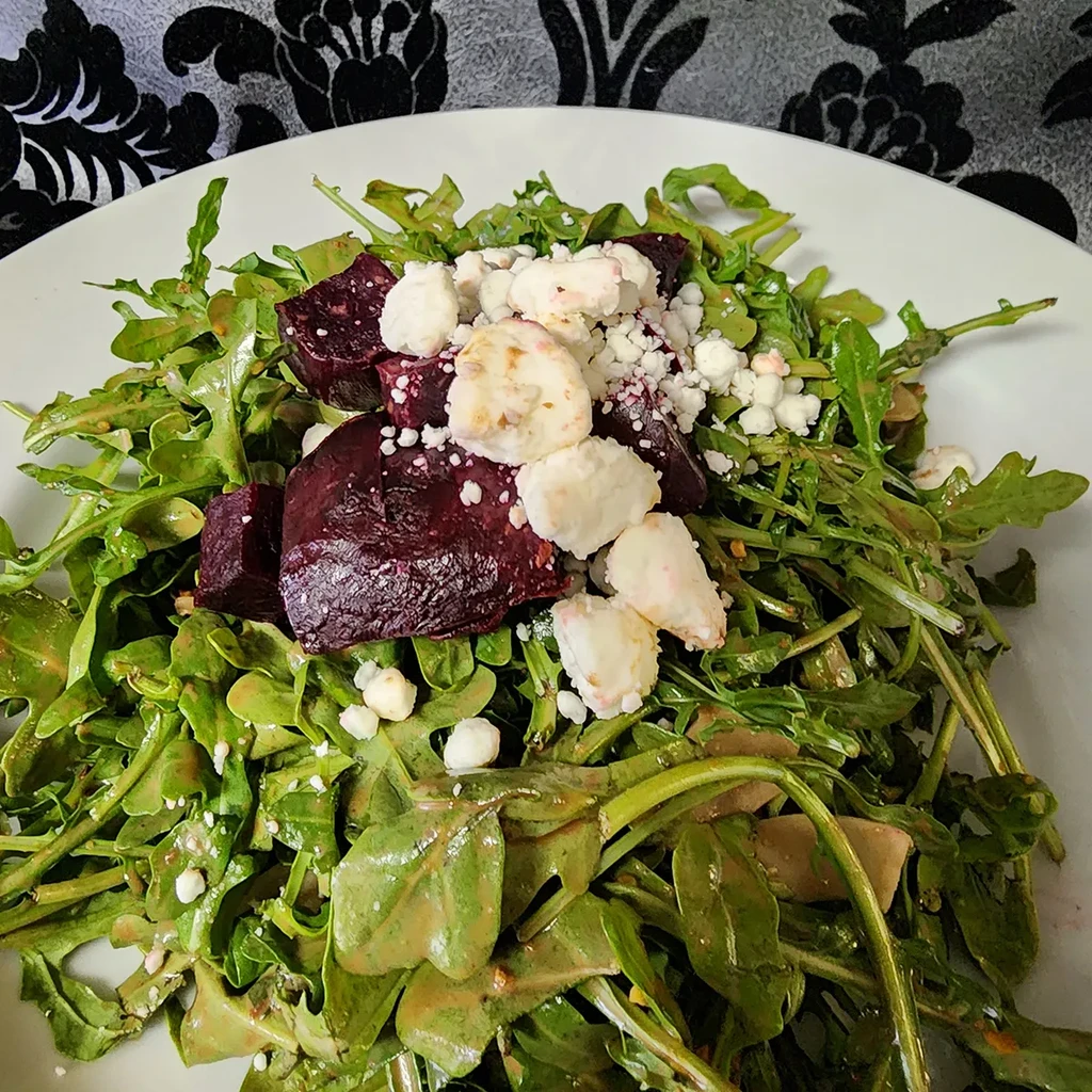 Arugula salad with dark red beets and crumbled white cheese.