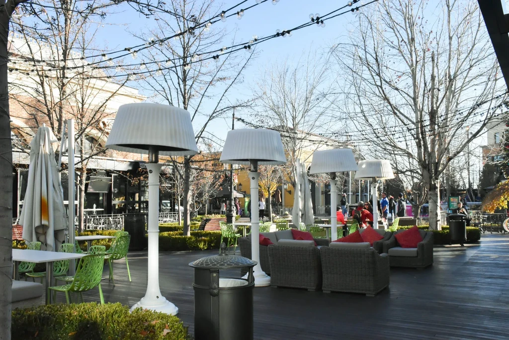 Expansive outdoor dining lounge area with patio heaters, colorful seating, string lights.
