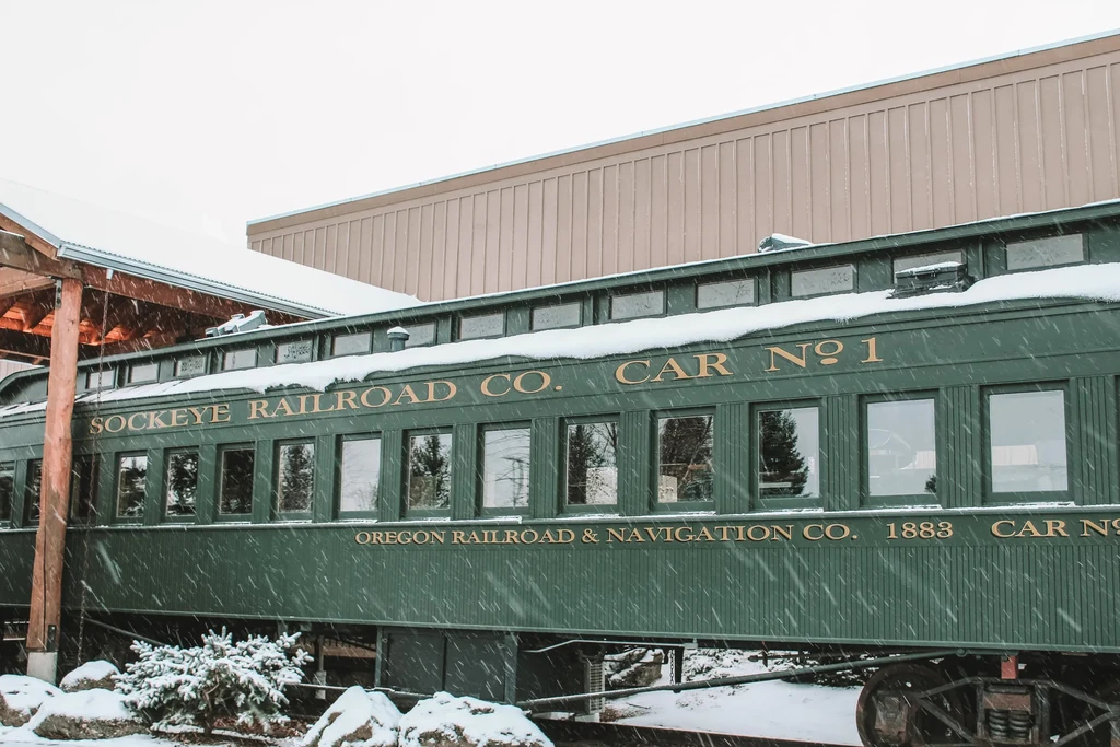 Vintage dark green Sockeye Railroad train car in falling snow.