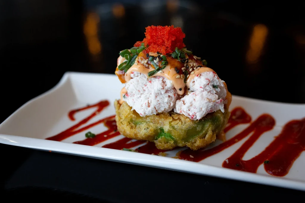 Tempura base with crab salad, tobiko, sauces, and green onion garnish.