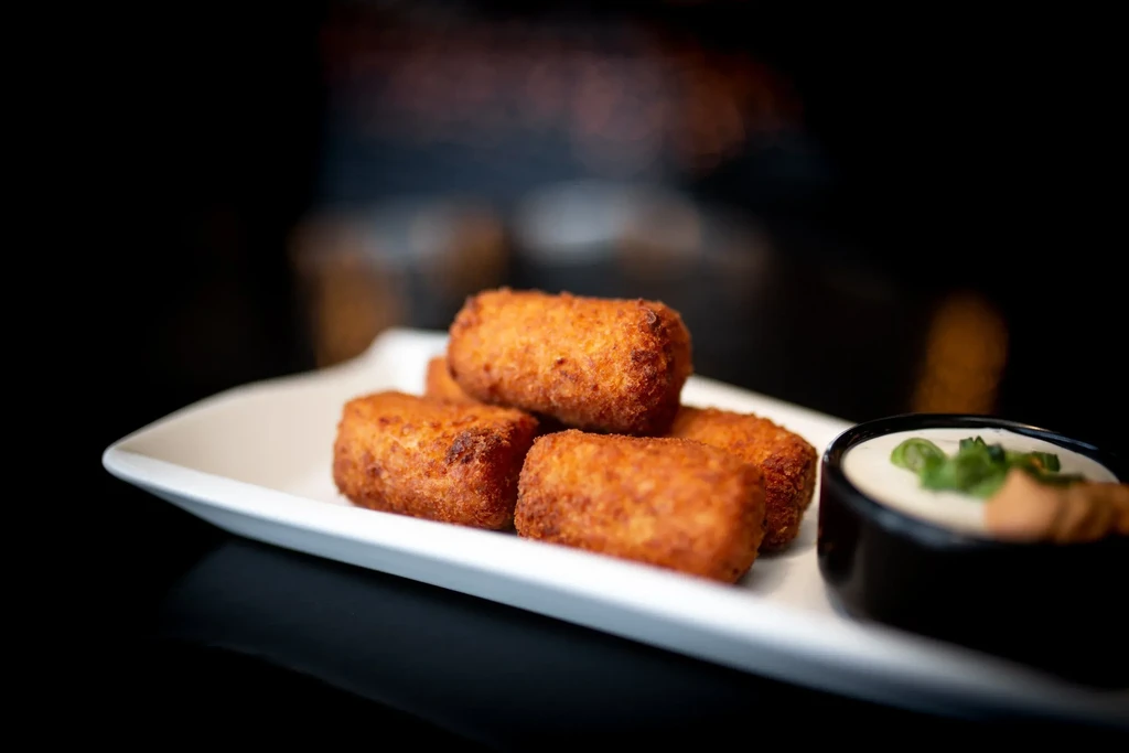 Golden-brown rectangular fried food with creamy green onion dipping sauce.