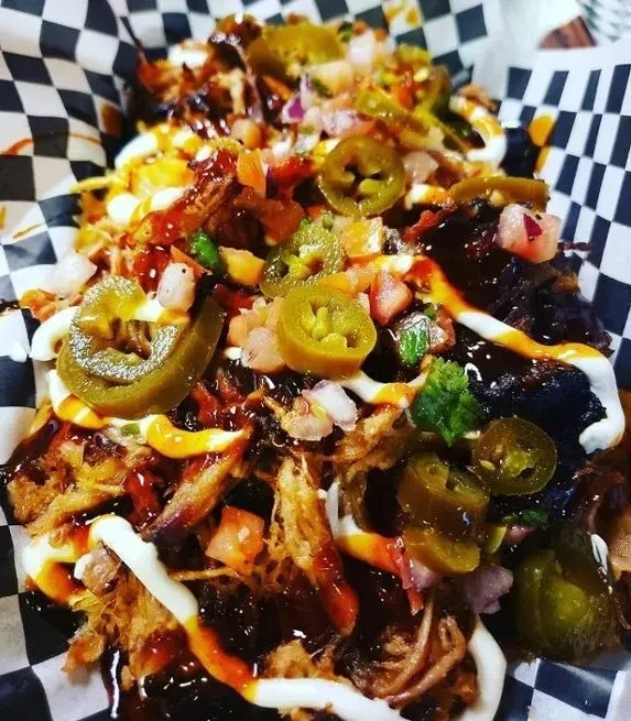 Loaded pulled pork nachos with BBQ sauce, jalapeños, and pico de gallo.