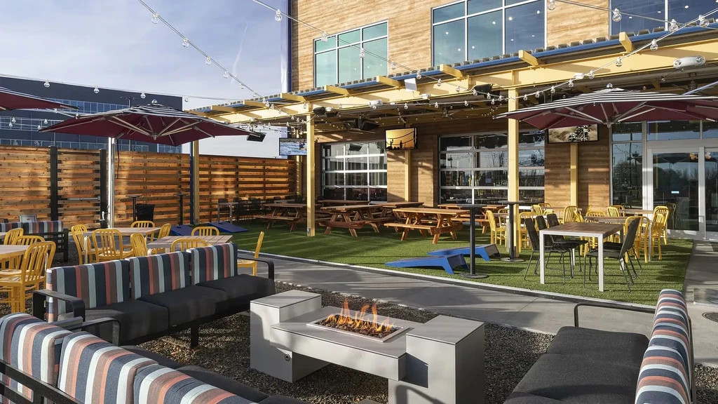 Modern outdoor patio with fire pit, lounge sofas, picnic tables, pergolas.