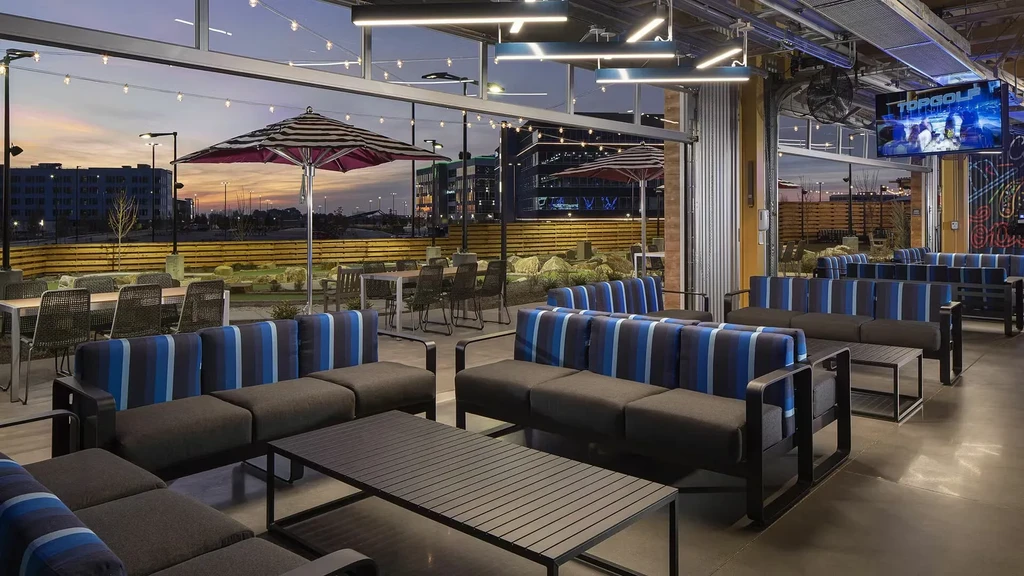 Modern Topgolf patio and lounge area at dusk, with cityscape.