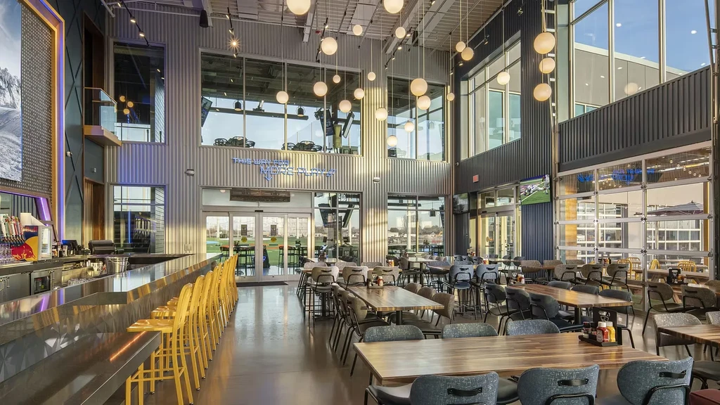 Empty modern restaurant and bar with yellow stools overlooking a golf course.