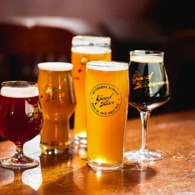 Five distinct beers on a wooden table, some branded.