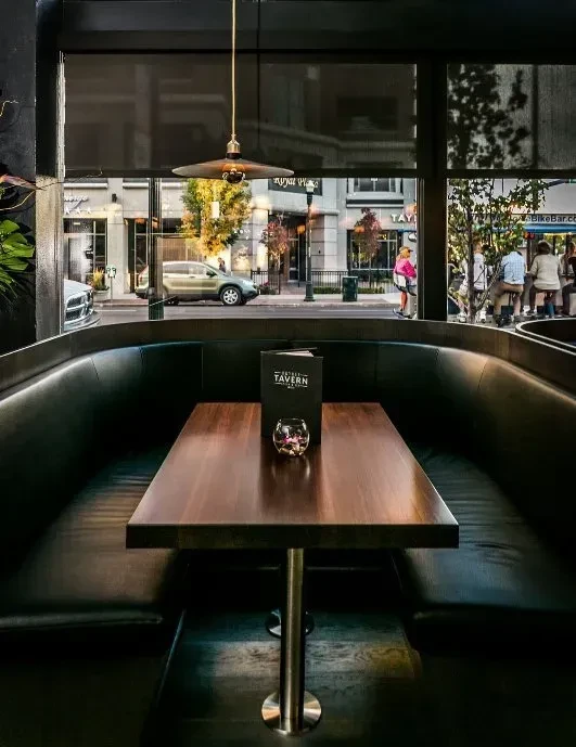 Sleek restaurant booth, warm light, menu, and lively autumn street view.