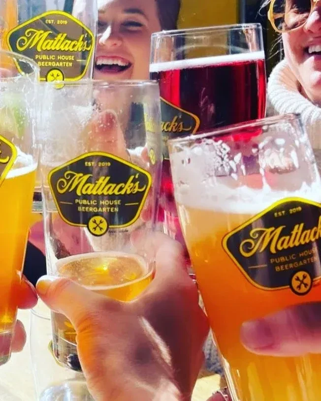 Smiling people toast Matlack's Public House beers in a group.