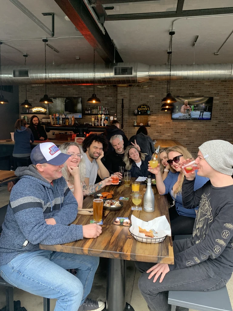 Lively group shares food and drinks at a casual bar table.