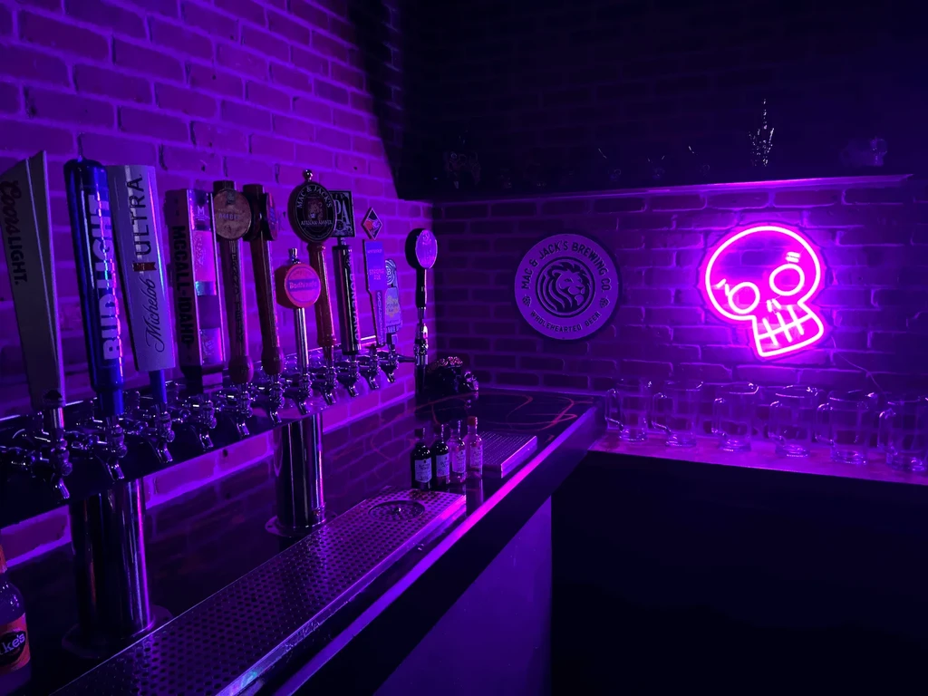 Purple-lit bar interior with beer taps, Mac & Jack's sign, and neon skull.