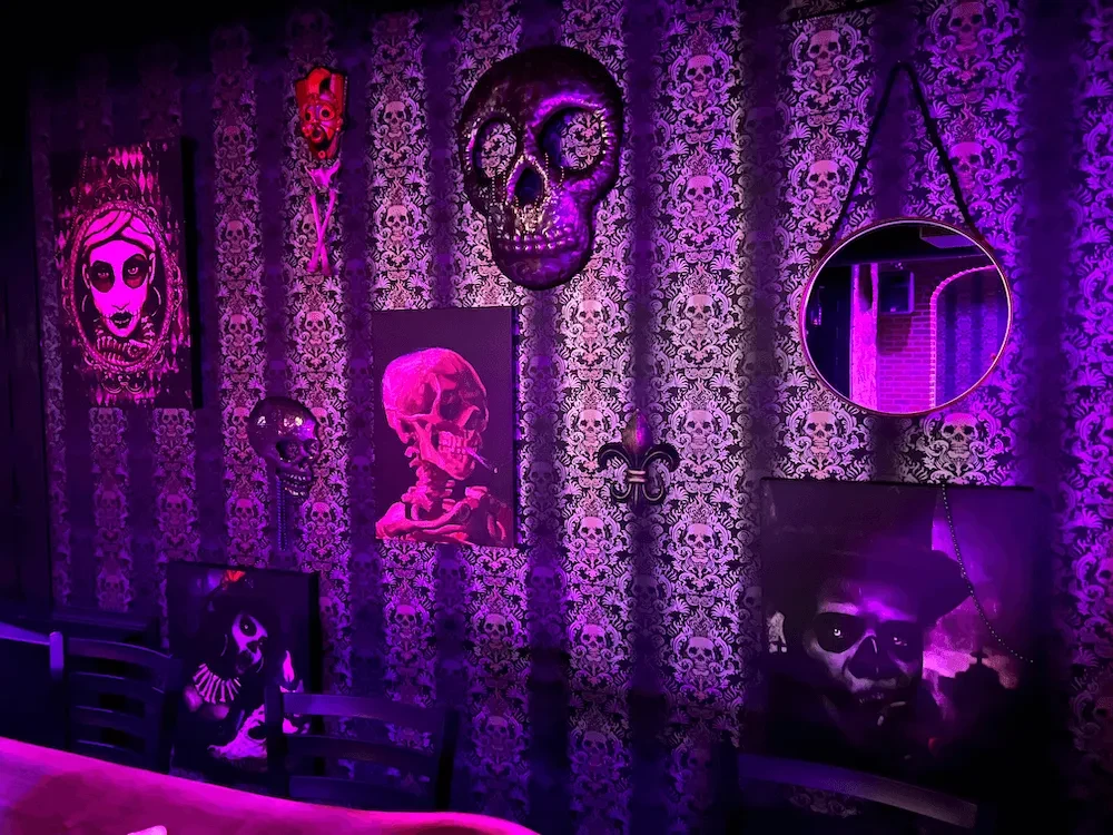 Purple-lit interior wall adorned with macabre skull and skeleton decor.