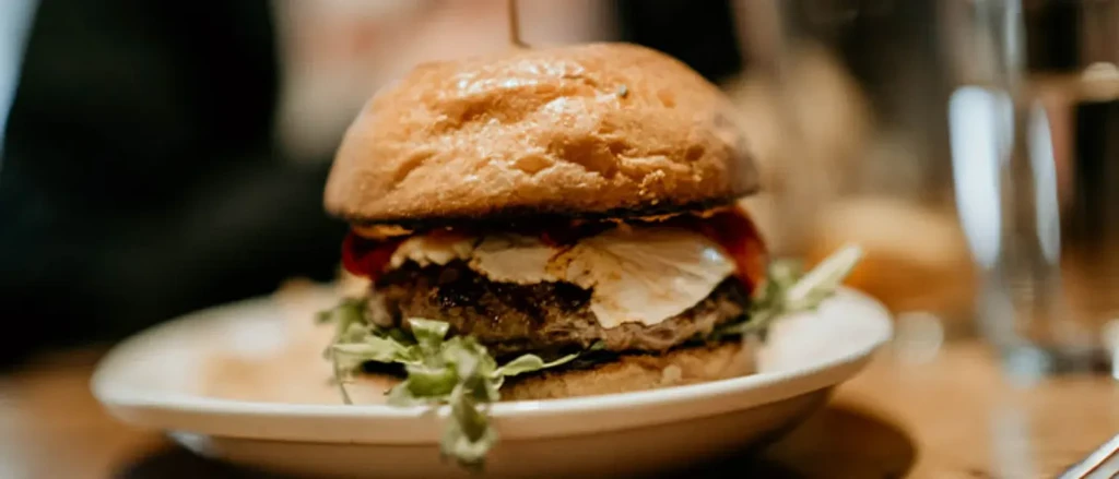 Close-up of gourmet hamburger with bun, patty, cheese, tomato, lettuce.
