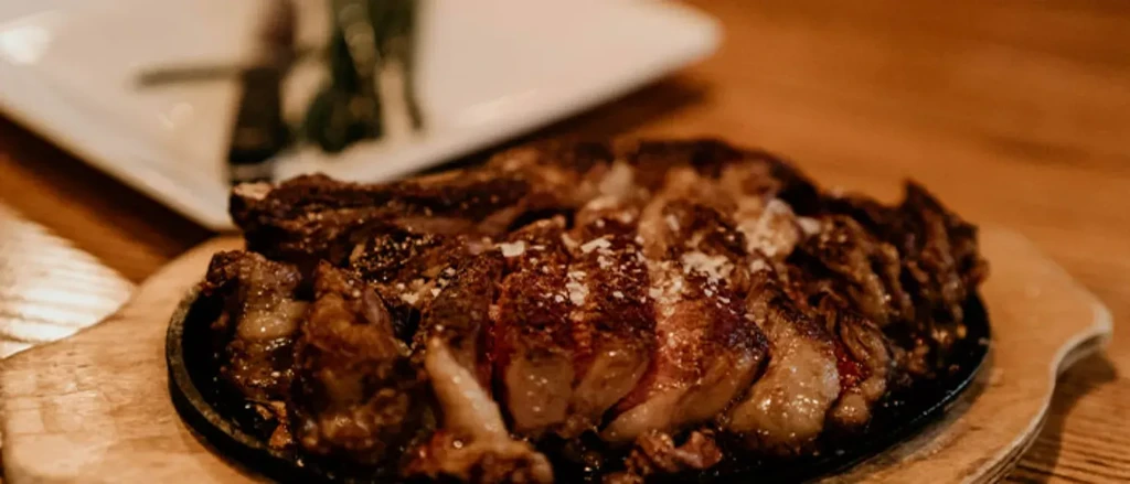 Richly cooked, seasoned, sliced steak in a cast iron skillet.