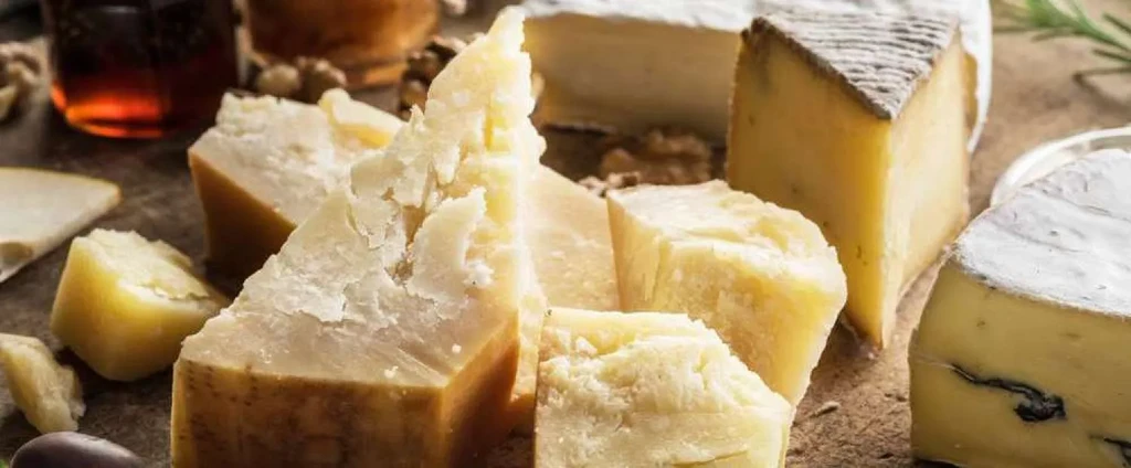 Close-up of a cheese board featuring diverse cheeses, nuts, and a jar.