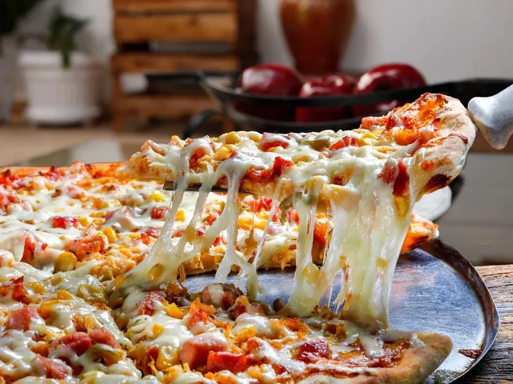 Close-up of a pizza slice being lifted, with stringy melted cheese.