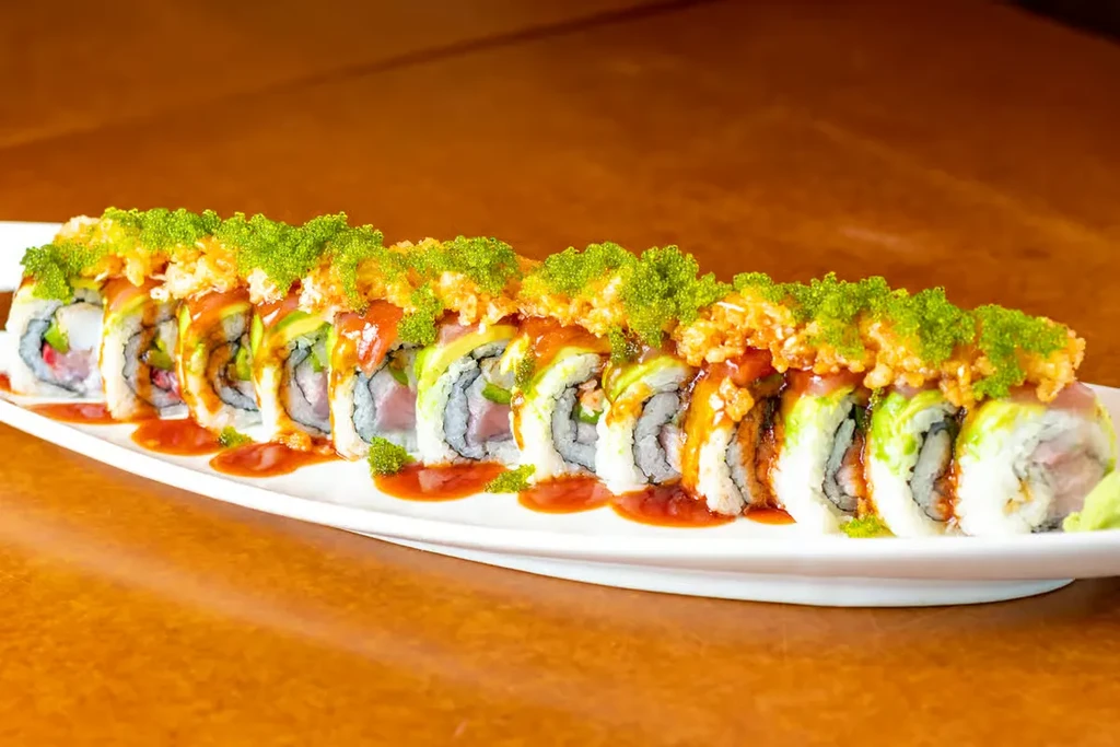 Uramaki sushi rolls with fish, avocado, tobiko, sauce, and wasabi.
