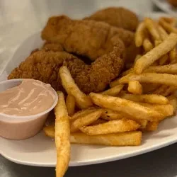 White plate with golden fried chicken tenders, french fries, and dipping sauce.