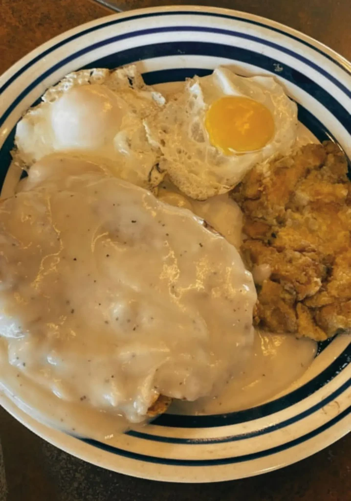 Close-up of chicken fried steak with gravy, two eggs, and fried potatoes.