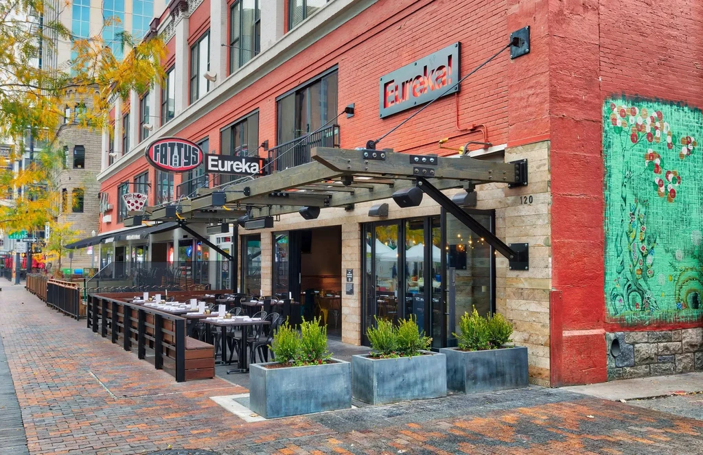 Urban restaurant Eureka! exterior with empty patio and autumn trees.