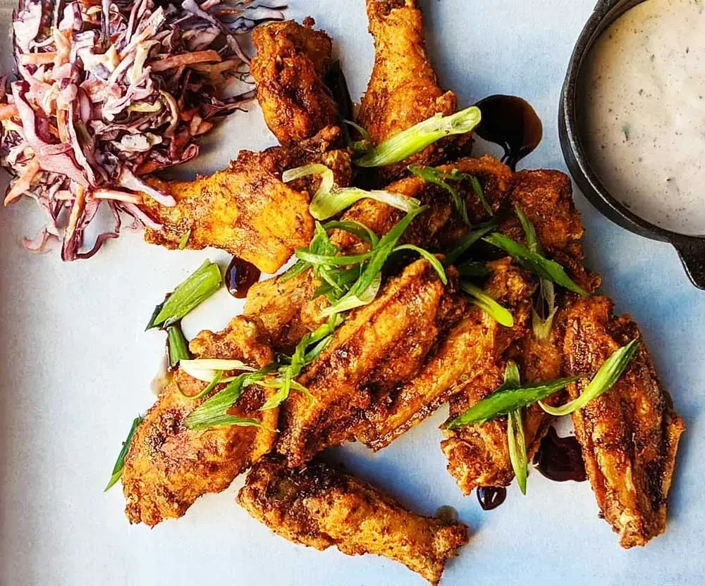 Golden fried chicken wings, coleslaw, sauce, and scallions.