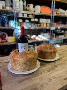 Red wine bottle inserted into one of two rustic baked goods.