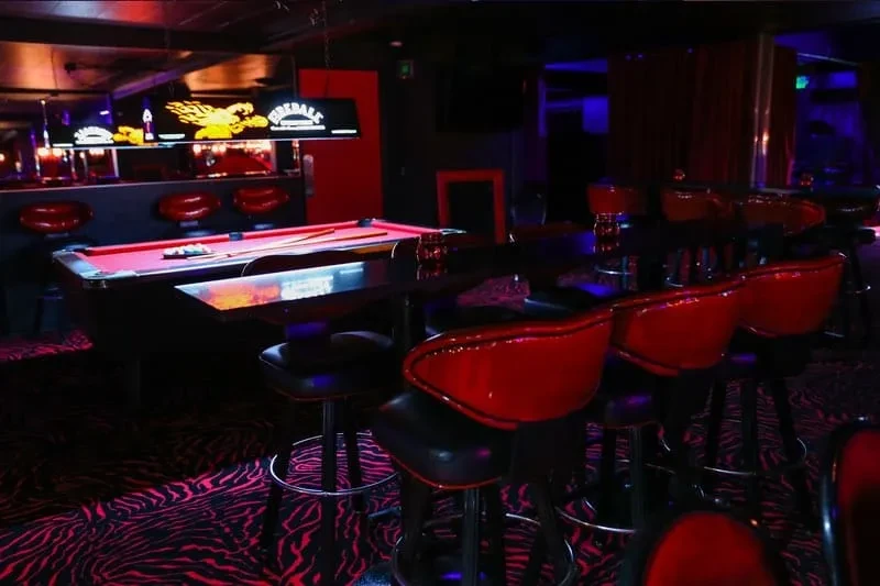 Dark bar with red pool table, "FIREBALL" sign, zebra floor.