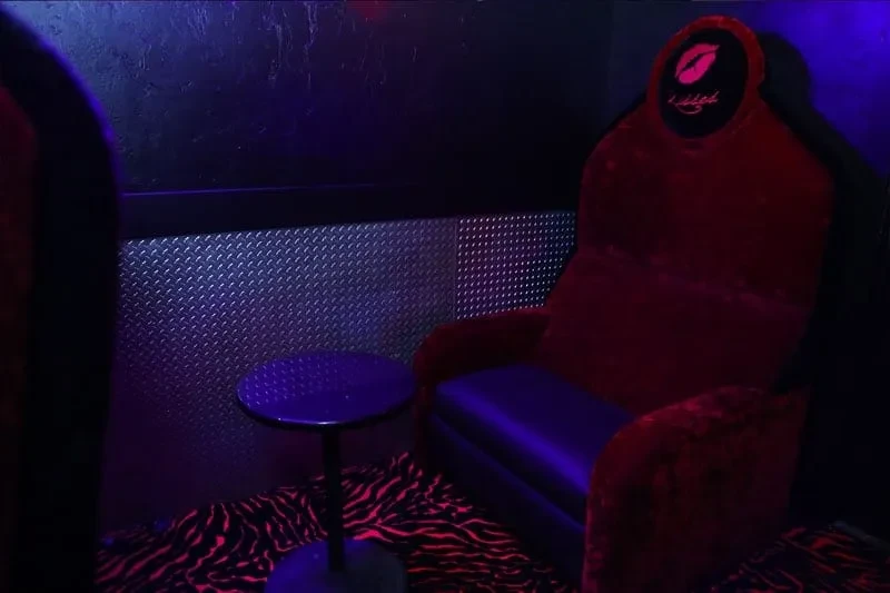 Dark lounge featuring a red velvet armchair with a Kisslab emblem.