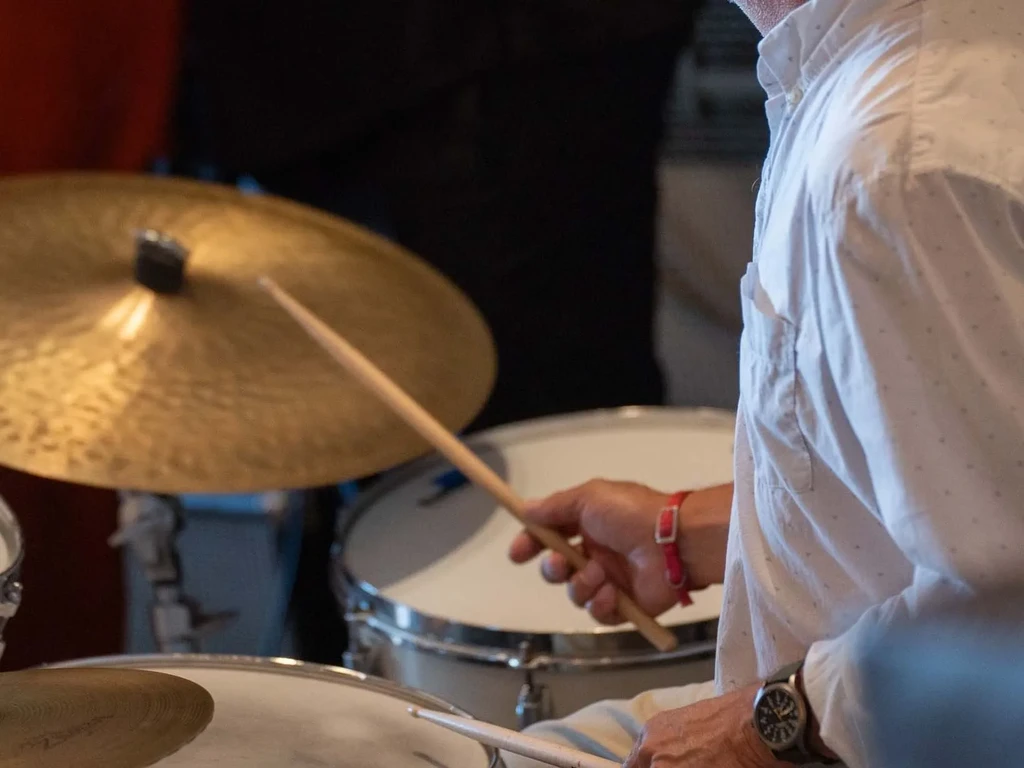 A drummer's hands and torso striking a drum kit during a performance.