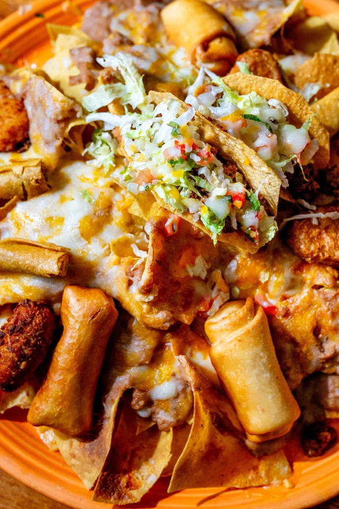 Overhead platter of Tex-Mex nachos, tacos, and taquitos.