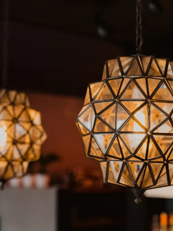 Ornate geometric pendant light with amber glass glows warmly.