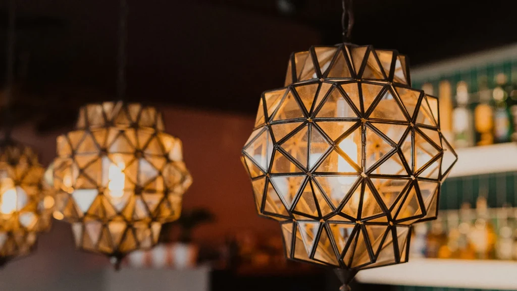 Ornate amber geometric light fixtures illuminate a blurred bar interior.