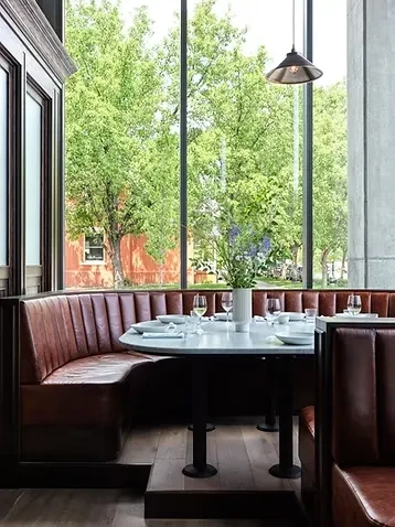 Empty modern restaurant booth by windows overlooking green trees.