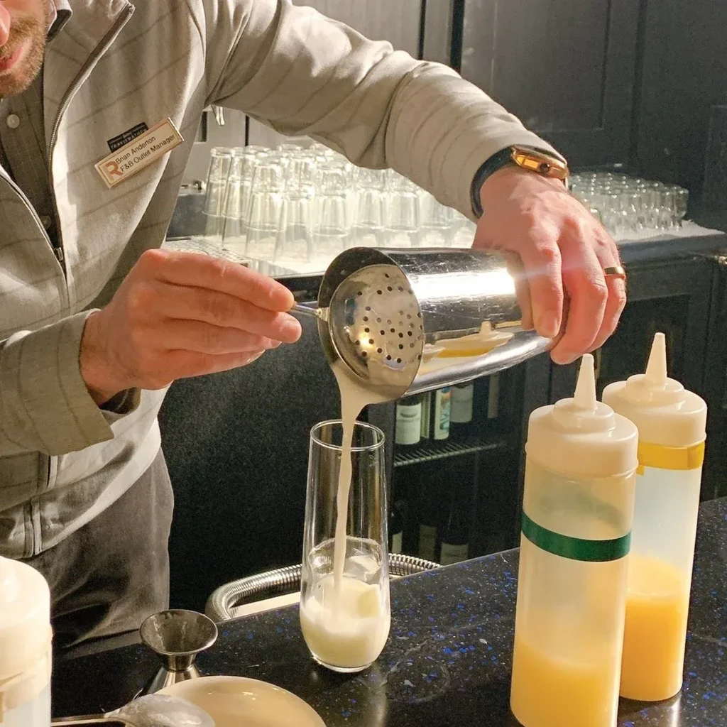 Manager Brian Anderton pours a creamy drink from a shaker.