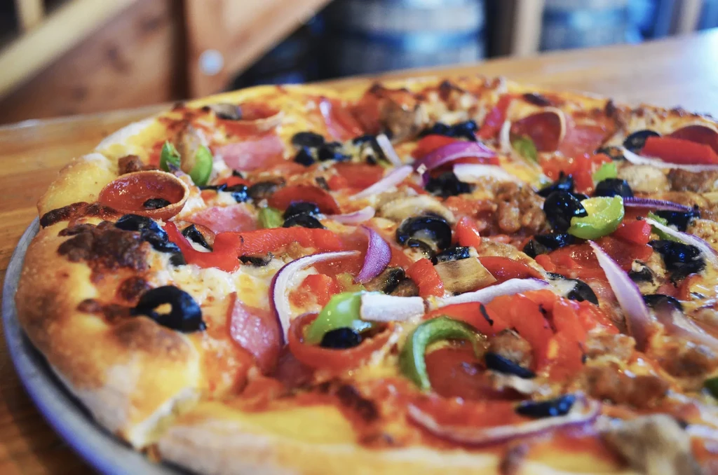 Close-up of a multi-topped pizza with melted cheese and golden crust.