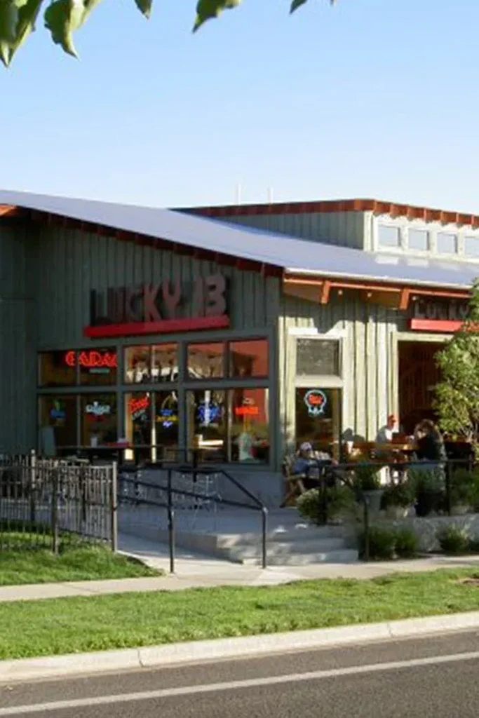 Lucky 13 restaurant with green siding, red roof trim, and outdoor patio.