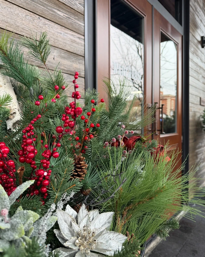 Winter holiday display: evergreens, red berries, silver poinsettias at Bourbonhouse.