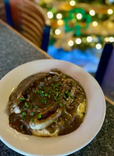 Mashed potatoes, sausages, and gravy topped with green chives.
