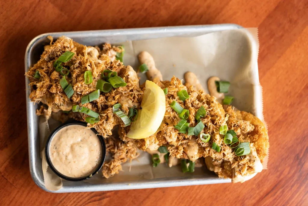 Fried protein topped with shredded meat, scallions, lemon, and creamy sauce.