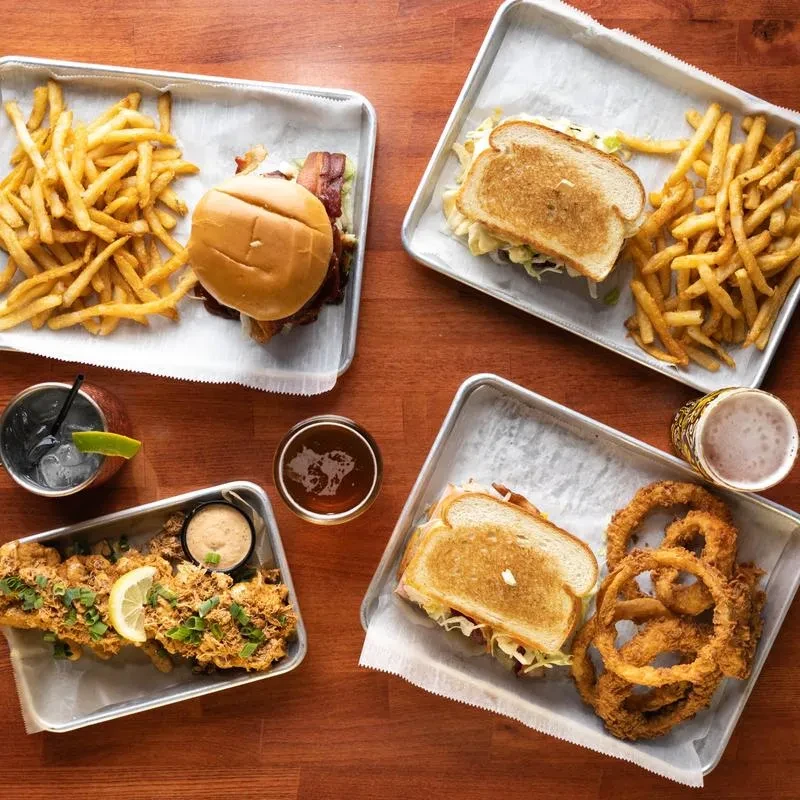 Top-down view of four casual meals and drinks on a wooden table.