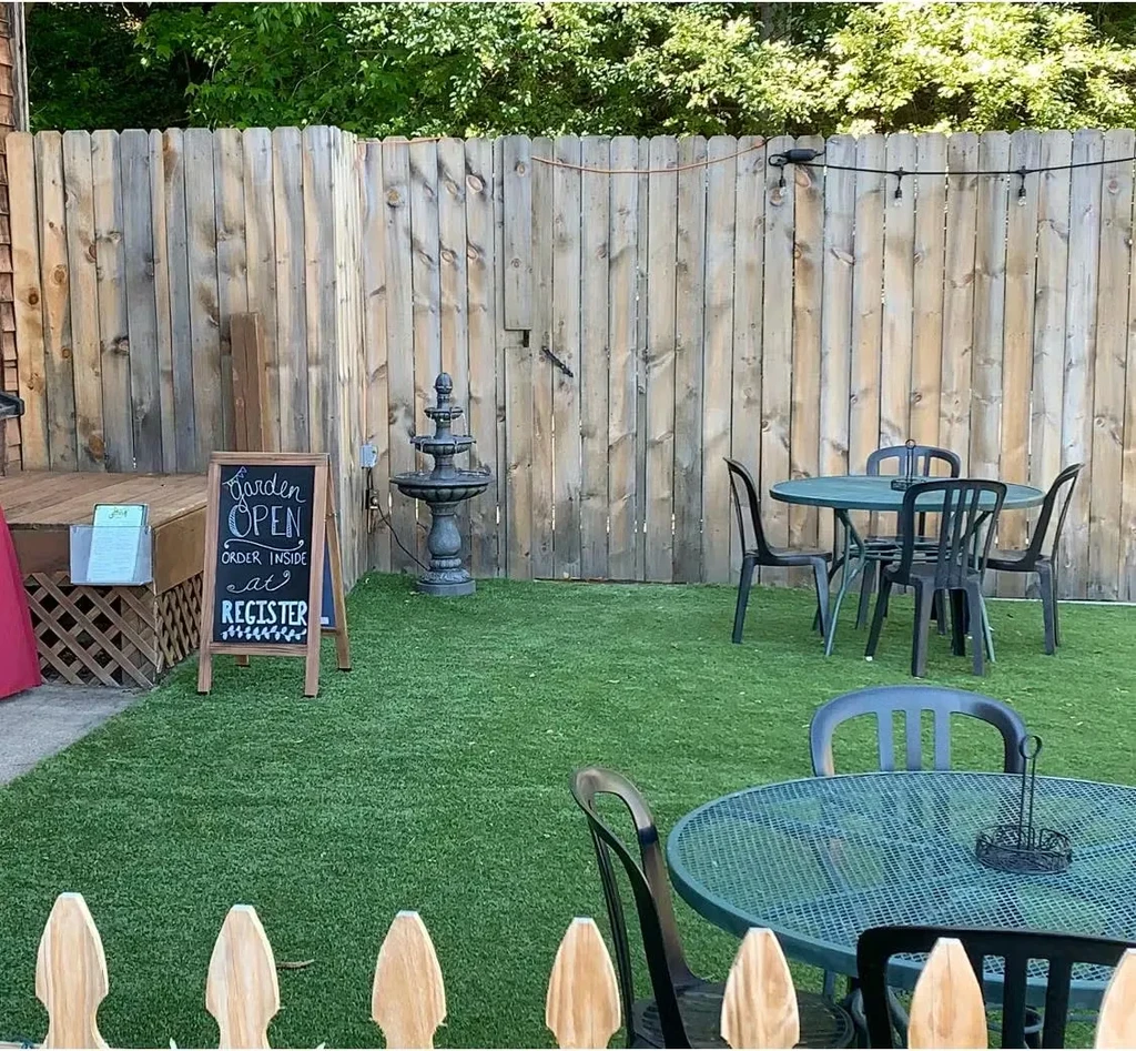 Garden patio with metal tables, water fountain, and 'Garden OPEN' sign.