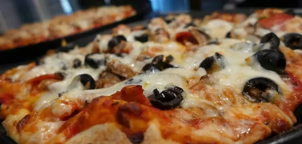 Freshly baked pizza with melted cheese, black olives, and mushrooms.