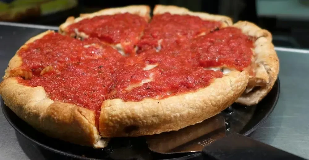 Deep-dish pizza, six slices, thick golden crust, rich tomato sauce.