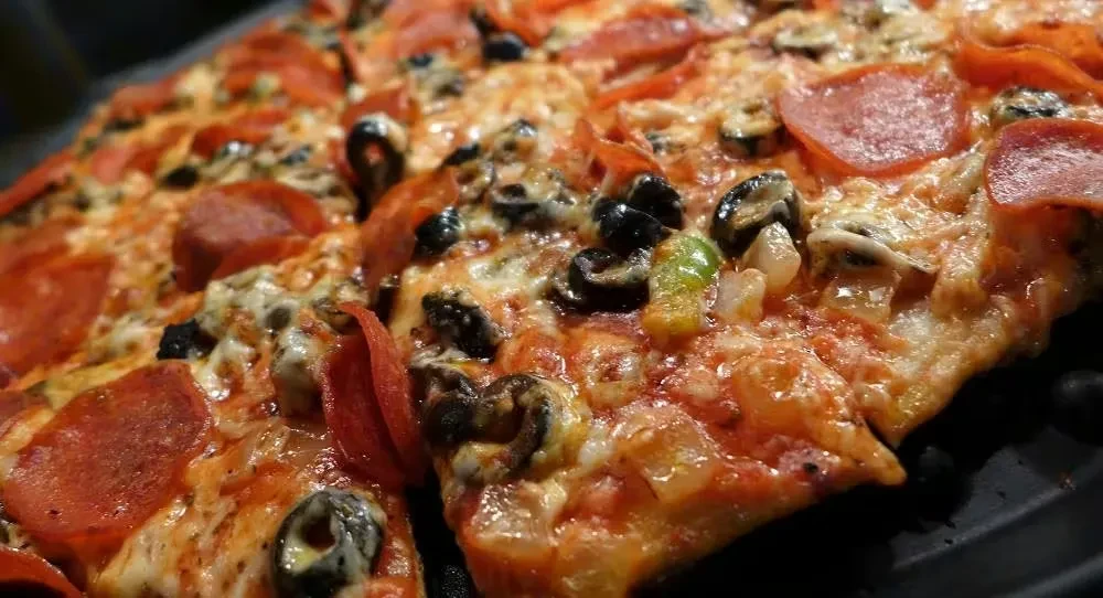 Freshly baked pizza topped with pepperoni, olives, and green bell peppers.