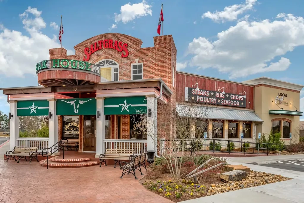 Saltgrass Steak House exterior: red brick, wood, green awnings, patio.