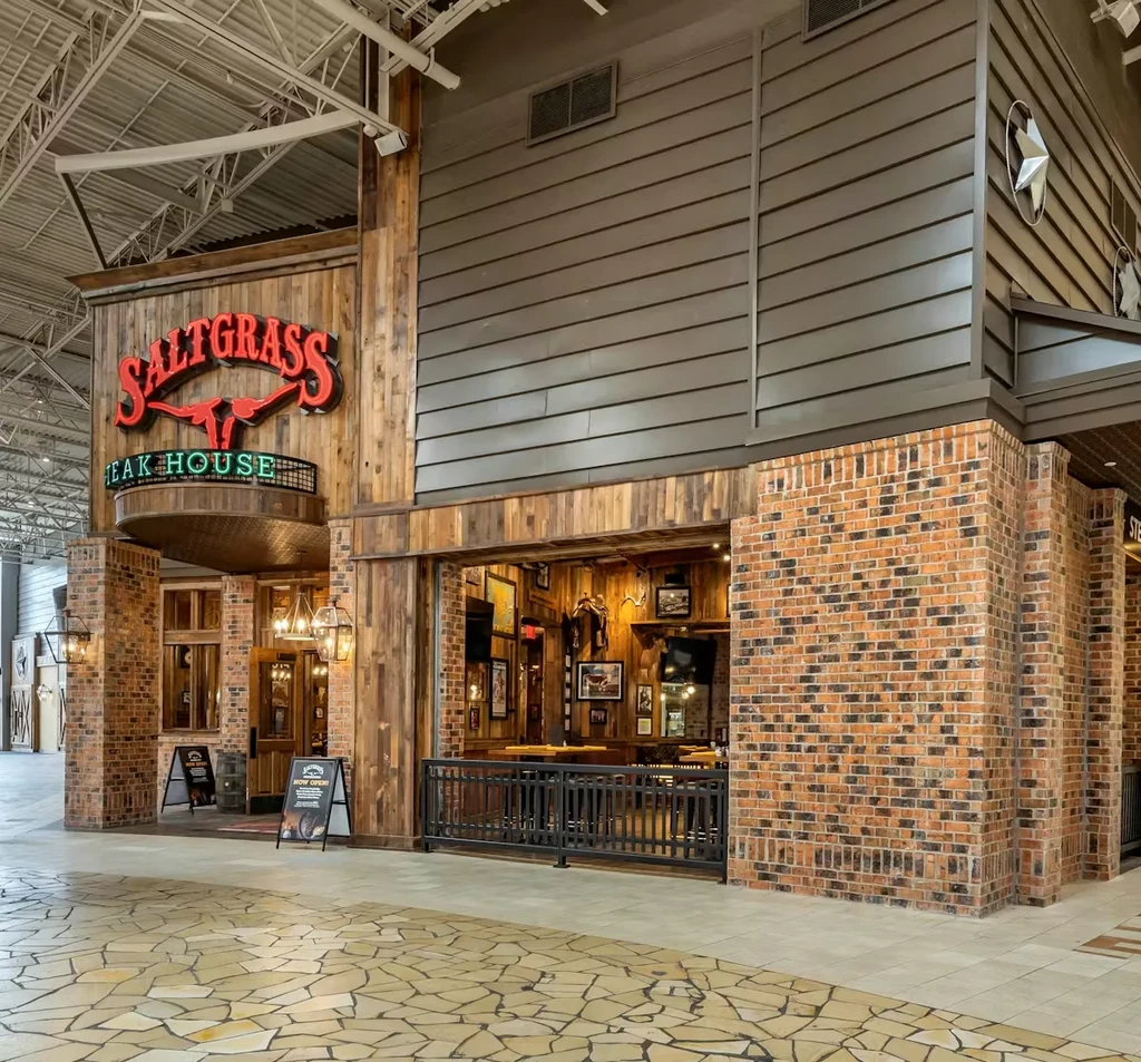 Rustic Saltgrass Steak House exterior with brick and wood in indoor complex.
