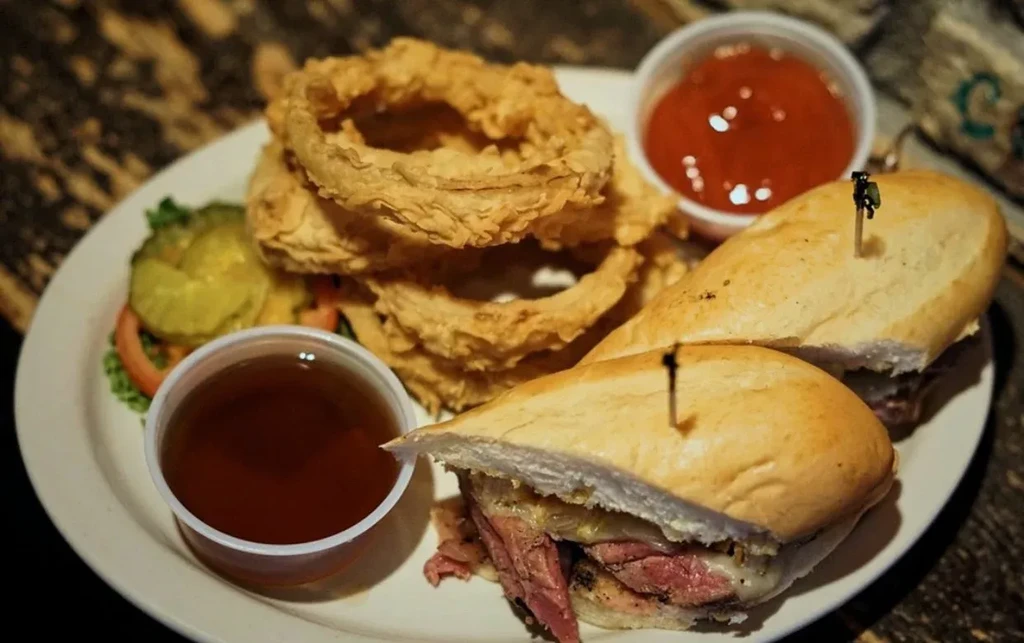 Roast beef sandwich halves, crispy onion rings, ketchup, and au jus.