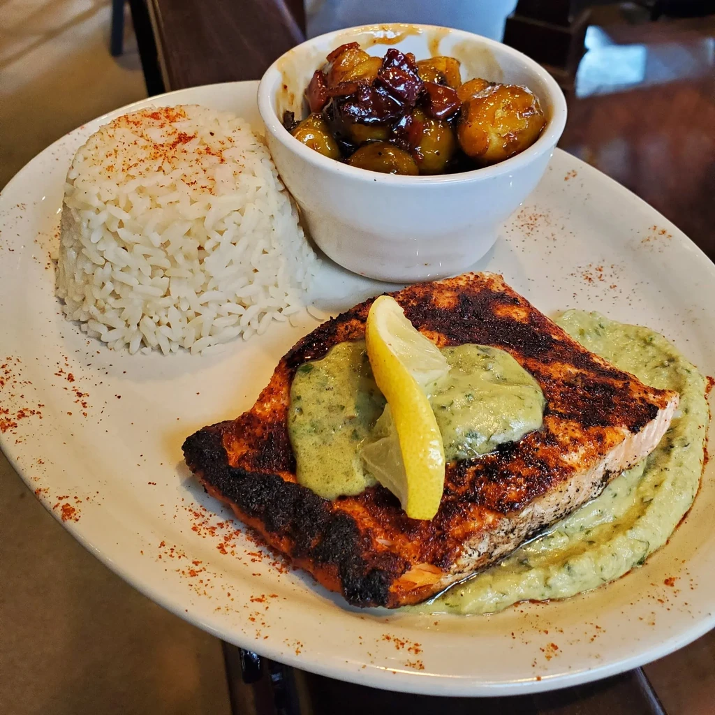 Seared salmon with green sauce, rice, and roasted vegetables.