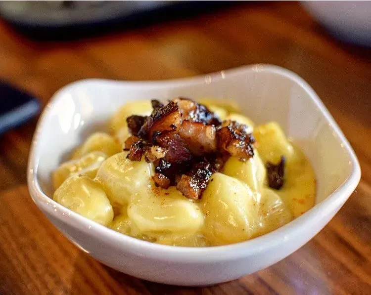 Creamy mac and cheese with crispy bacon bits in a white bowl.