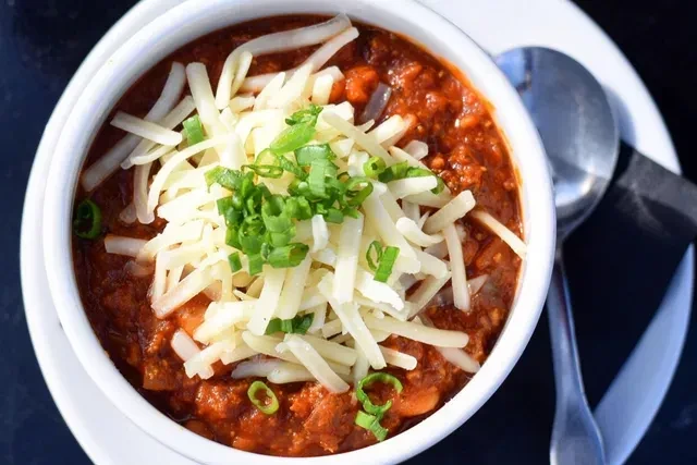 Overhead shot of chili with shredded cheese and green onions.